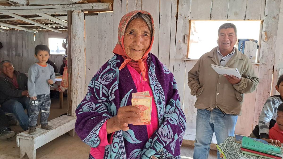 Mujer de la comunidad mostrando con una sonrisa el dinero que ha ahorrado en su grupo