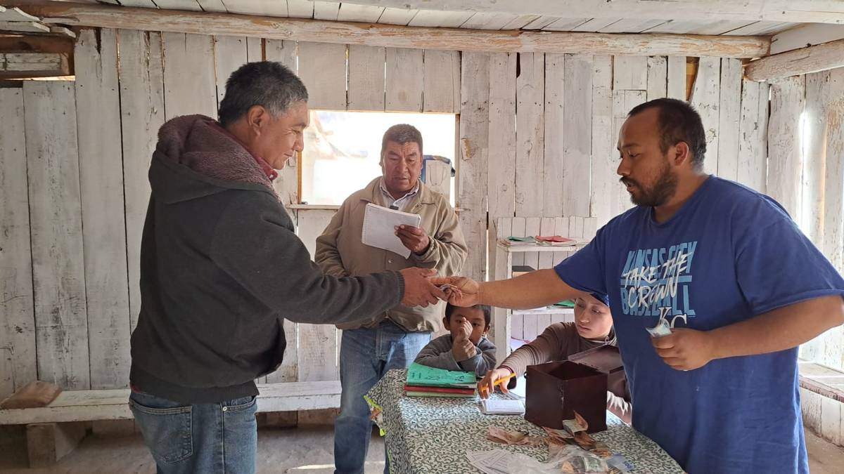 Integrante de un grupo de ahorro entregando su ahorro durante la reunión semanal
